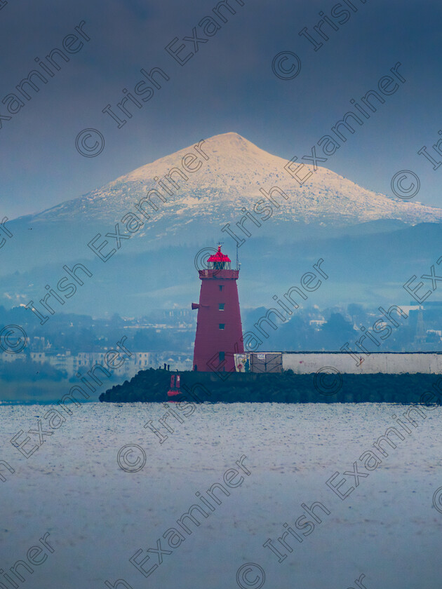 Poolbeg Lighthouse Sugar Loaf snow 8 January 2025 
 The Great Sugar Loaf mountain aligned with Poolbeg Lighthouse from Dollymount Strand, Co. Dublin during a cold spell of weather in January 2025. Perspective compressed using a 450mm full frame equivalent lens and a Nikon D7500. Picture: Sryan Bruen